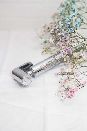 Hygiene and cleanliness concept. New hygienic chrome-plated shower in hand against a background of white tiles. Bathroomの写真素材