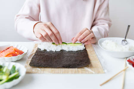 Sushi cooking process, girl makes sushi with different flavorsの写真素材