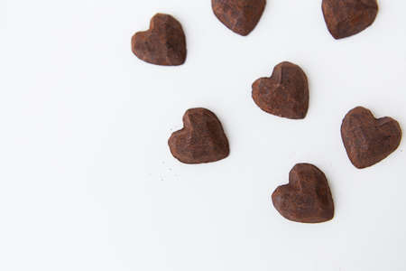 Chocolate candies with a truffle in the form of a heart on a white background, close-up. Place for an inscriptionの写真素材