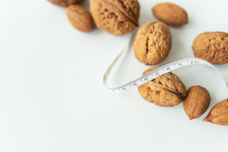 Beautiful whole walnut kernels, whole nuts in shell on a white table. Centimeter among nuts, low calorie nuts. selective focusの写真素材