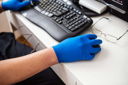 A doctor in blue gloves quickly collects data about a patient. The concept of healthcare and taking care of your health. Workplace of a doctor, online consultationの写真素材