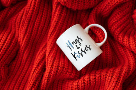 Hugs and kisses inscription on a white cup on a red knitted fabric. love concept. St. Valentine's Dayの写真素材