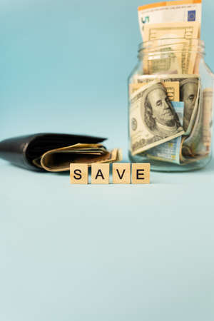 International money 100 dollar bills lie in a leather wallet, next to a bank with banknotes and the inscription saveの写真素材