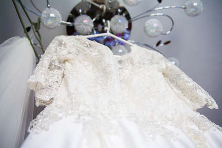 White wedding dress embroidered with beads hanging on chandelierの写真素材