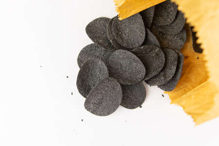 selective focus. Macro chips in a craft bag. Spices and salt on black chips. Black chips with spices...
