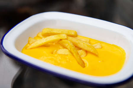 The concept of fast food and fast food. French fries sit in a plate along with cheddar cheese sauce. top view, close-upの写真素材