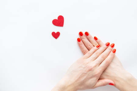 Nail care and manicure. Beautiful female hands with a red nail and a red heart. Place for an inscription. Valentine's Dayの写真素材