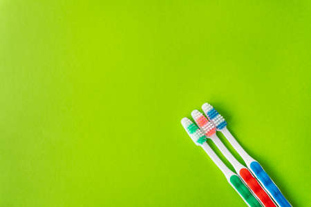 Multi-colored toothbrushes on a green background, the concept of dental care and hygiene. Place for an inscriptionの写真素材