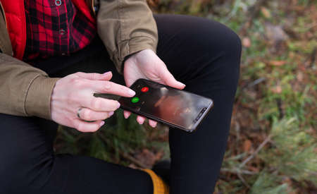 The girl sits on a log in the forest and receives a call from a loved one. Travel, trekking and hikingの写真素材