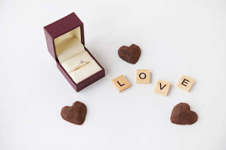 The inscription in wooden letters love, small truffle sweets in the form of a heart. Diamond ring...