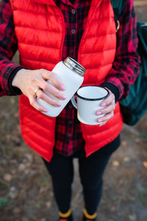 A girl pours hot tea from a thermos, a snack in the open air.Travel, trekking and hikingの写真素材