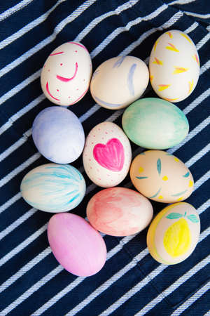 Beautiful Easter eggs painted with watercolors lie on a striped blue fabric. Easter holiday conceptの写真素材