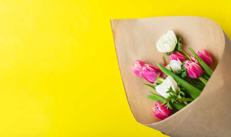 Red and white bouquet of tulips and anemones flowers on a yellow background. With copy spaceの写真素材