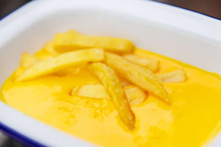 The concept of fast food and fast food. French fries sit in a plate along with cheddar cheese sauce. top view, close-upの写真素材