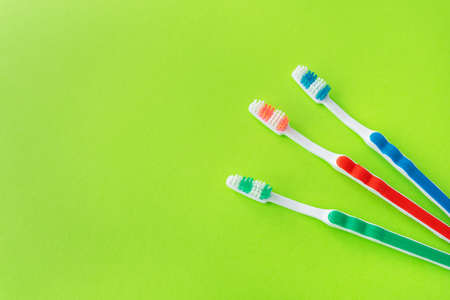 Multicolored toothbrushes on a green background, the concept of dental care and oral hygiene. Place for an inscriptionの写真素材