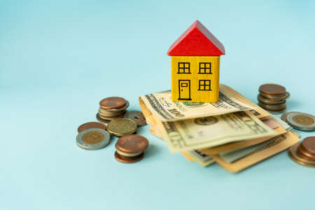 Money in international currency, including euro, dollar, a coin on which there is a toy house. The concept of mortgages, investments, loans, debts, housing purchases: apartments or housesの写真素材