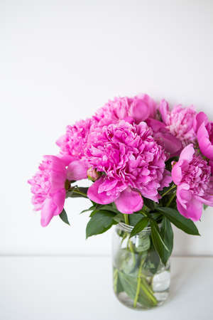 Beautiful bouquet of pink peony flowers in a vase on a white table. Flower surprise on March 8の写真素材