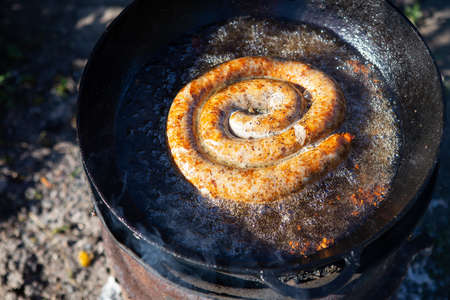 Homemade pork sausages in a rustic frying pan with different spices. outdoor recreationの写真素材