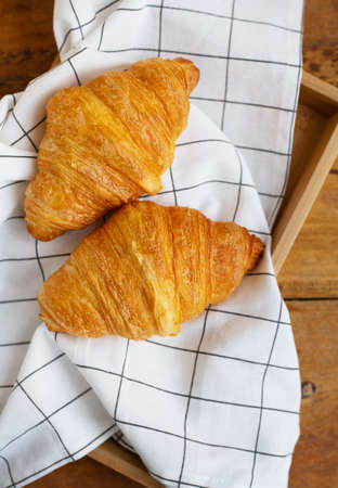Breakfast in bed, fresh croissants and a cup of coffee on a wooden tray. fine morningの写真素材