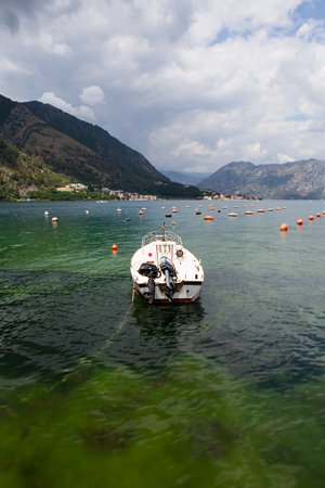 Very beautiful embankment of the Bay of Kotor, a small fishing boat. Montenegro. A beautiful and cozy city, tiled houses. The concept of rest and vacation in Europeの写真素材