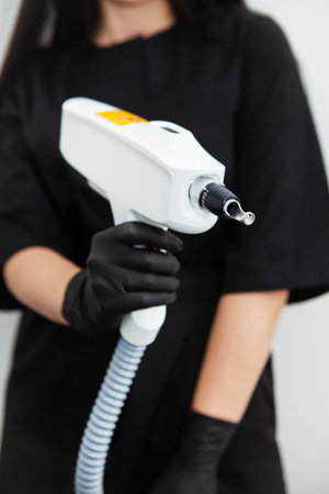 The master of laser hair removal holds a laser hair removal machine in his hands. Removal of hair on all parts of the body. hair removal machineの写真素材