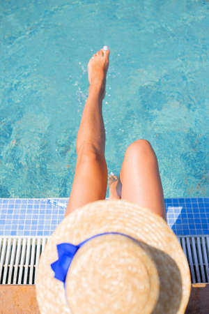 Beautiful girl in a hat near a blue pool - sun, summer, heat. top view.の写真素材