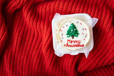 Christmas cake with the inscription merry christmas, decorated with icing, on a red background, top...