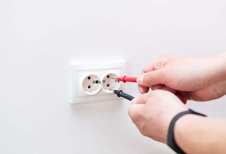 Measuring the voltage in the socket with a professional digital multimeter. Profession electrician,...