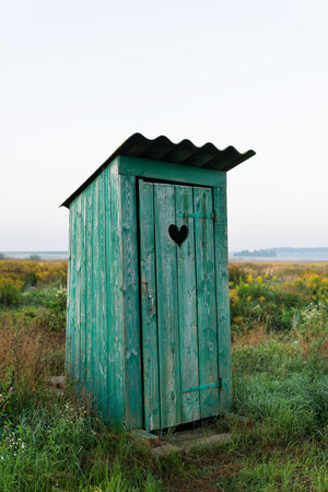 Heart shape on the old wooden toilet door, green toilet in the field. outdoor recreationの写真素材
