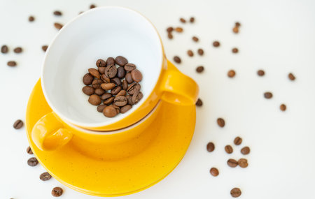 Beautiful morning, the process of making coffee, a yellow cup on a white table, scattered coffee beansの写真素材