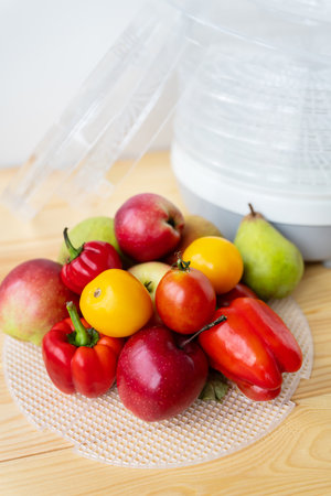 Electric dryer for dehydrating products. Various vegetables on the background of the device. Side view, close-up, natural lightingの写真素材
