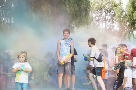 Lviv, Ukraine - July 18, 2021: Color Holi Festival, a crowd of people adults and small children throw colorful paint. Indian holiday, children running on a wooden stageのeditorial素材