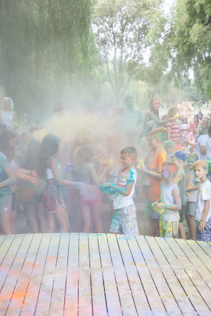 Lviv, Ukraine - July 18, 2021: Color Holi Festival, a crowd of people adults and small children throw colorful paint. Indian holiday, children running on a wooden stageのeditorial素材