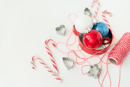 Christmas candies, along with cookie cutters, Christmas tree toys and red thread for gift wrapping, lie on a white table. Selective focus, noise. Christmas and New Year 2023-2024の写真素材