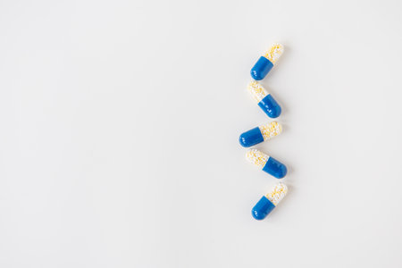 Medical pills-capsules, half blue on a white background, lying in a row. Flat layout, top view. Concept of medicine and healthcareの写真素材
