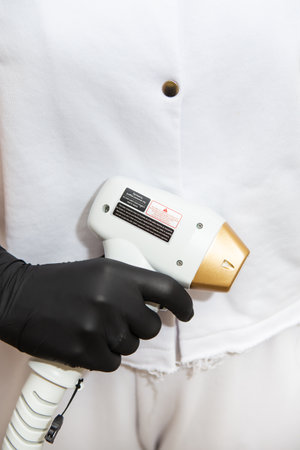 The doctor holds in his hands a device for laser hair removal. The concept of skin care, hair removal in the spa salonの写真素材