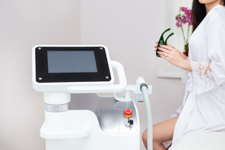 Professional laser hair removal machine, screen for setting up the hair removal process. Professional cosmetology, body epilation. Body care concept, client in the backgroundの写真素材