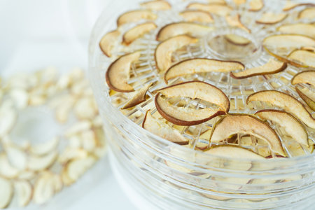 The process of homemade dried fruit or candied fruit in an electric dryer on the table. Fruits for storage and consumption in winter. Apples and pears are already dried in a dryer. close-upの写真素材