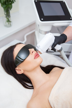 The process of laser hair removal of the female body. professional cosmetology, epilation of the face and upper lip area. girl in goggles. body care conceptの写真素材
