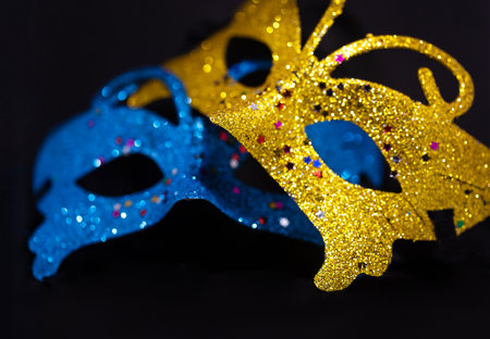 Yellow and blue shiny venetian carnival mask isolated on black background. New Year's party, hide your face. close-upの写真素材