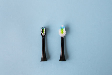 Modern electric toothbrush on a blue background, it's time to change the brush - old and new brush attachment. Hygiene concept for daily oral careの写真素材