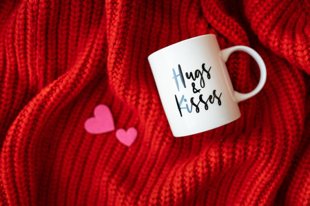 Hugs and kisses inscription on a white cup on a red knitted fabric. love concept. St. Valentine's Dayの写真素材