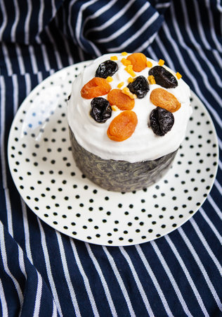 An Easter cake decorated with dried apricots and prunes stands on a plate and a striped blue apron. Easter religious holiday conceptの写真素材