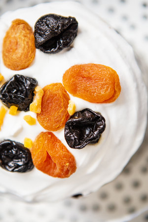An Easter cake decorated with dried apricots and prunes stands on a striped blue apron. Easter religious holiday conceptの写真素材