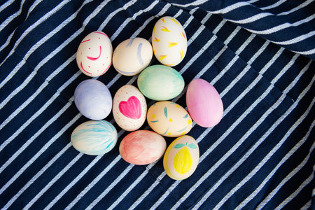 Beautiful Easter eggs painted with watercolors lie on a striped blue fabricの写真素材