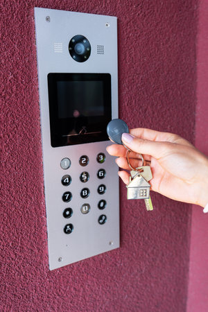 A young woman types the apartment code on the electronic intercom panel, opens the door with a sensor key. protection and security conceptの写真素材