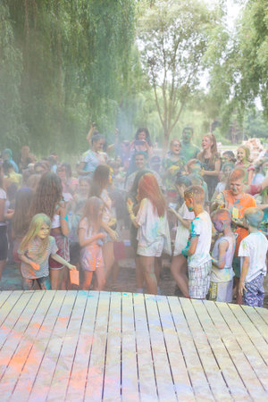 Lviv, Ukraine - July 18, 2021: Color Holi Festival, a crowd of people adults and small children throw colorful paint. Indian holiday, children running on a wooden stage, poor visibility due to paint dustのeditorial素材