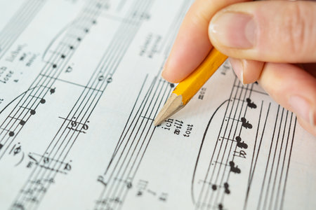 Lviv, Ukraine - December 13, 2022: Piano score, musical notes on paper. The hand makes notes with a pencil on paper. View from aboveのeditorial素材