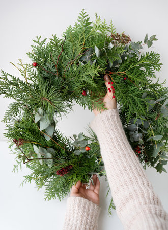 Stylish Christmas wreath for the interior, hang the wreath on the door. Handmade, the girl holds a freshly made wreath in her hands. The atmosphere of the holiday, Christmas and New Yearの写真素材