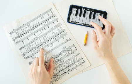 Lviv, Ukraine - December 13, 2022: The program on the phone to play the piano, piano score. Musical notes on paper. The program on the smartphone, practice. View from aboveのeditorial素材